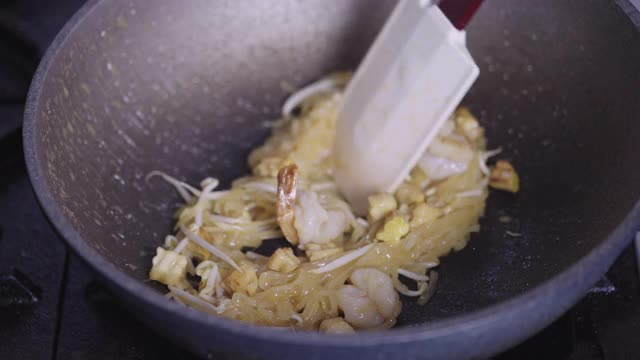 SLO MO:在做泰式炒粉或炒面时，用手放入鸡蛋。视频素材