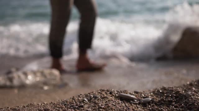在海滩上散步的人。海浪碰到了他的脚视频素材