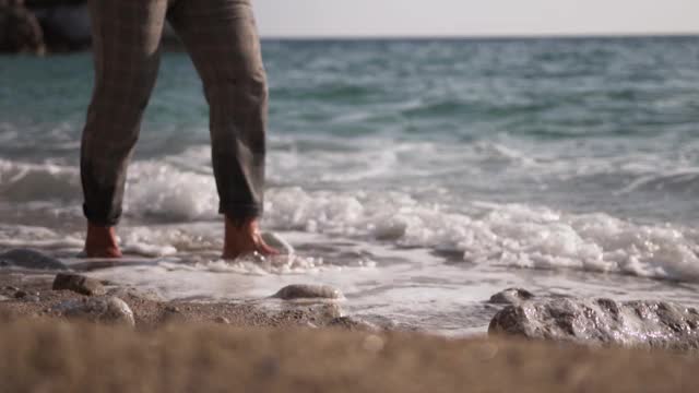 在海滩上散步的人。海浪碰到了他的脚视频素材