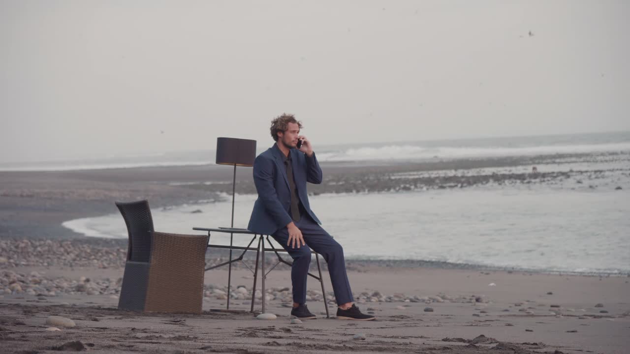 一名男子在孤立的海滩上打电话视频下载