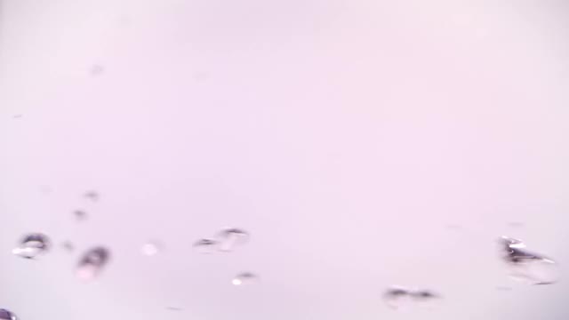 近距离微距和超级慢动作的浮动清澈的粉红色的水滴在粉红色的背景视频素材