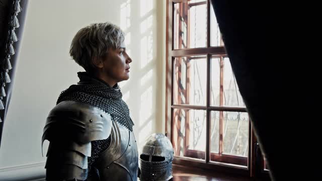 在一座古老的宫殿里，一名身强力壮的中世纪女武士站在窗前，情绪激动地准备战斗视频素材