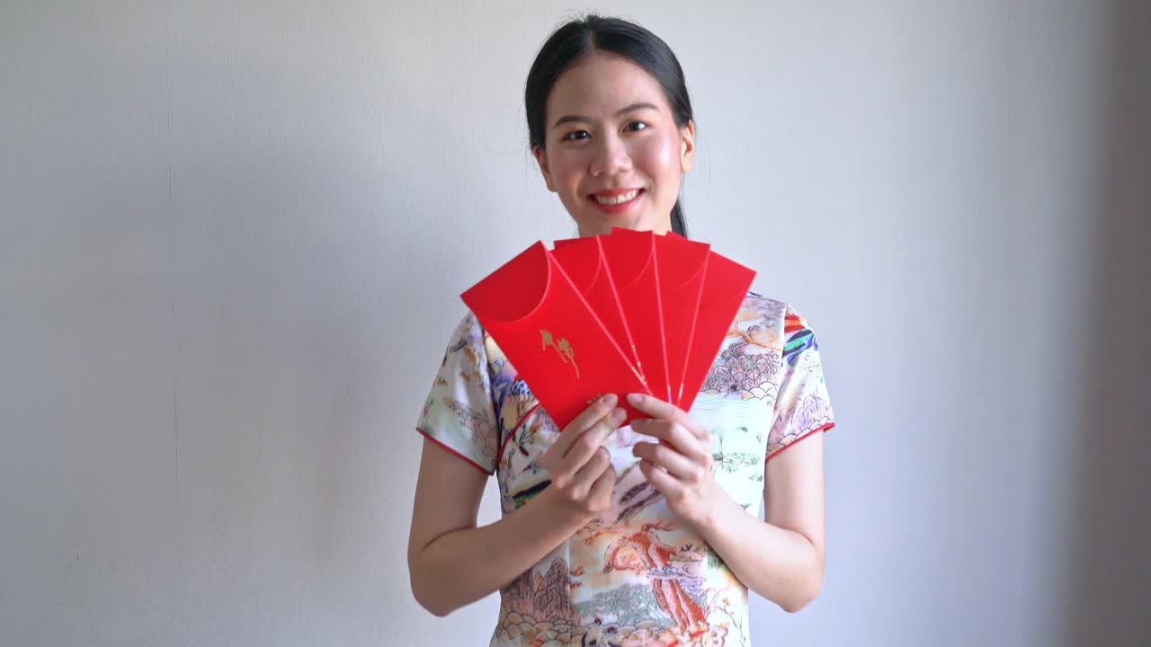美丽的亚洲妇女穿着带有红包的中国传统服装视频下载