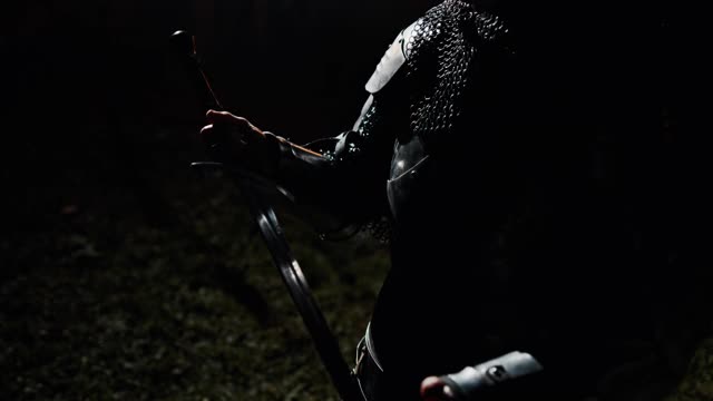女骑士在夜里检查剑。倾斜的剪影的女人在贞德服装检查剑，而准备战斗在晚上视频素材