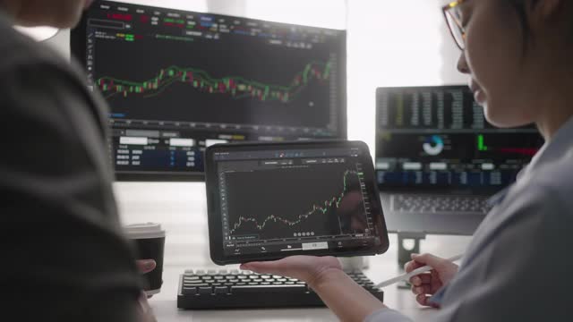 两位女商人分析数字平板电脑上的股票数据视频素材