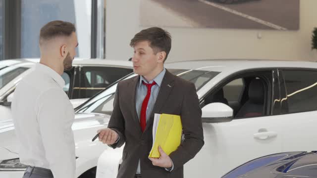 一个愉快的汽车经销商在给顾客车钥匙后与他握手视频下载