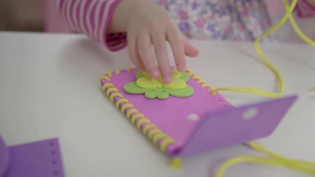 年轻女孩在家里用塑料针和纱线缝制垫子工艺视频下载