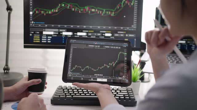 两个女商人使用数字平板电脑分析股票市场数据图视频素材
