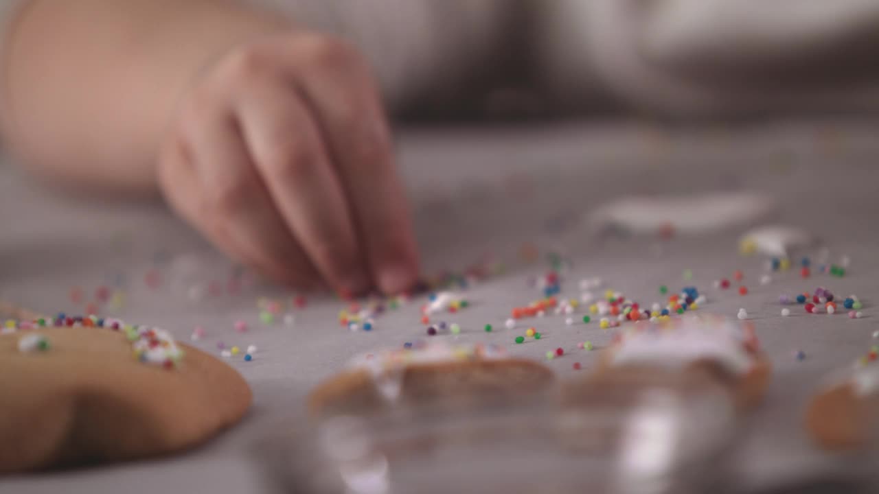 小女孩正在装饰姜饼，她正在收集糖屑，撒在饼干上视频下载