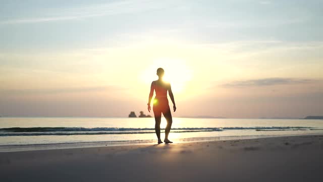 在海滩上做瑜伽的运动女人的剪影视频下载