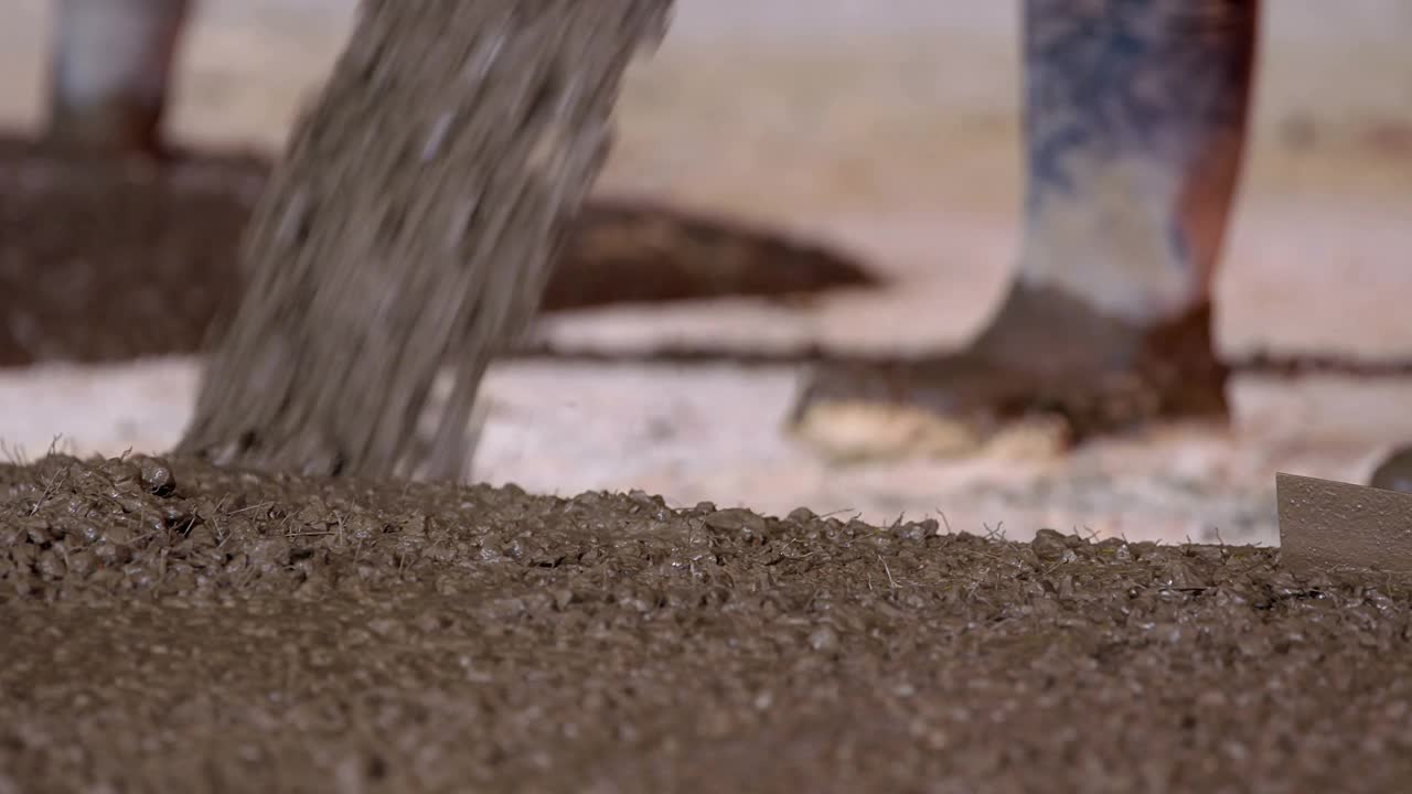 在建筑工地，工人们用自动搅拌机浇筑混凝土视频素材
