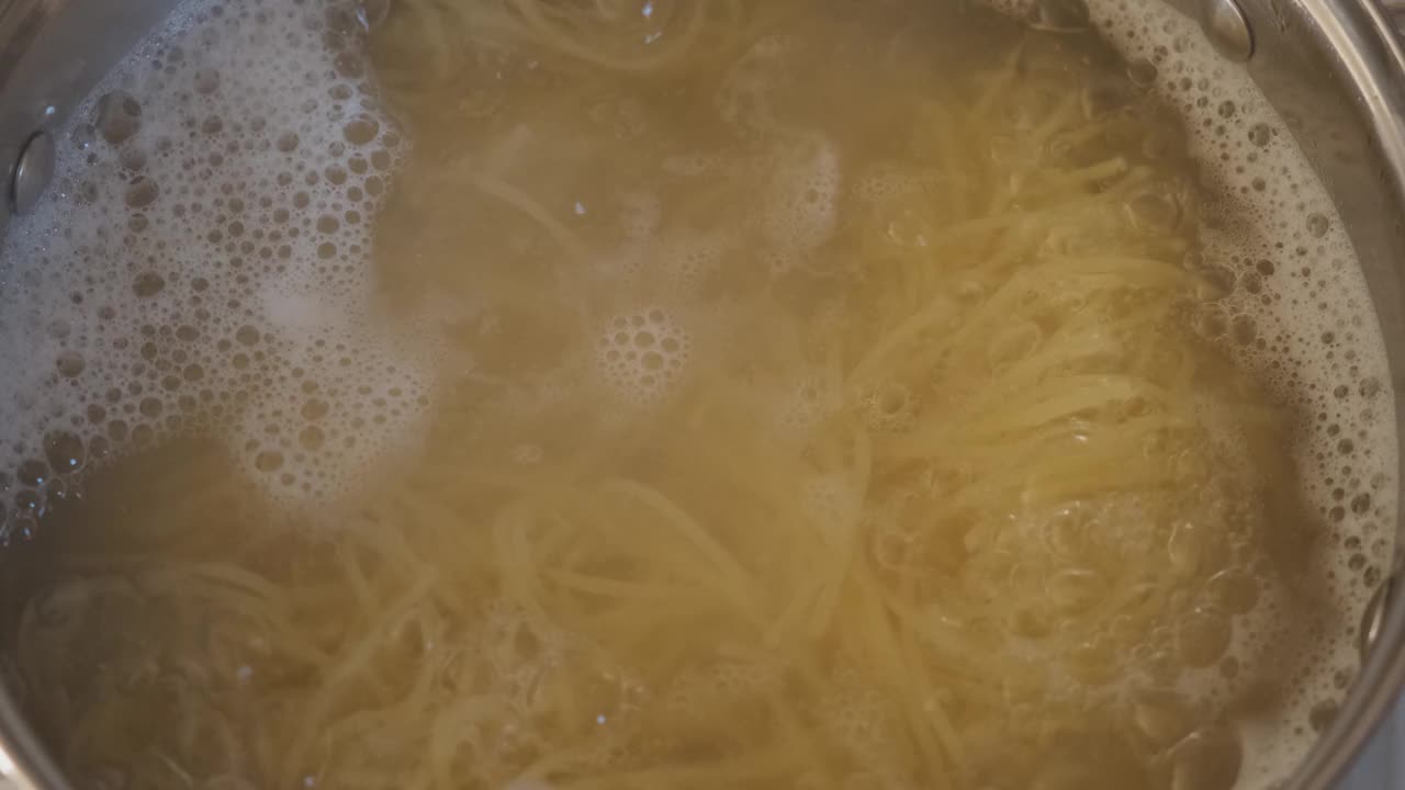 用手在炉子上的沸水中搅拌意大利面视频素材
