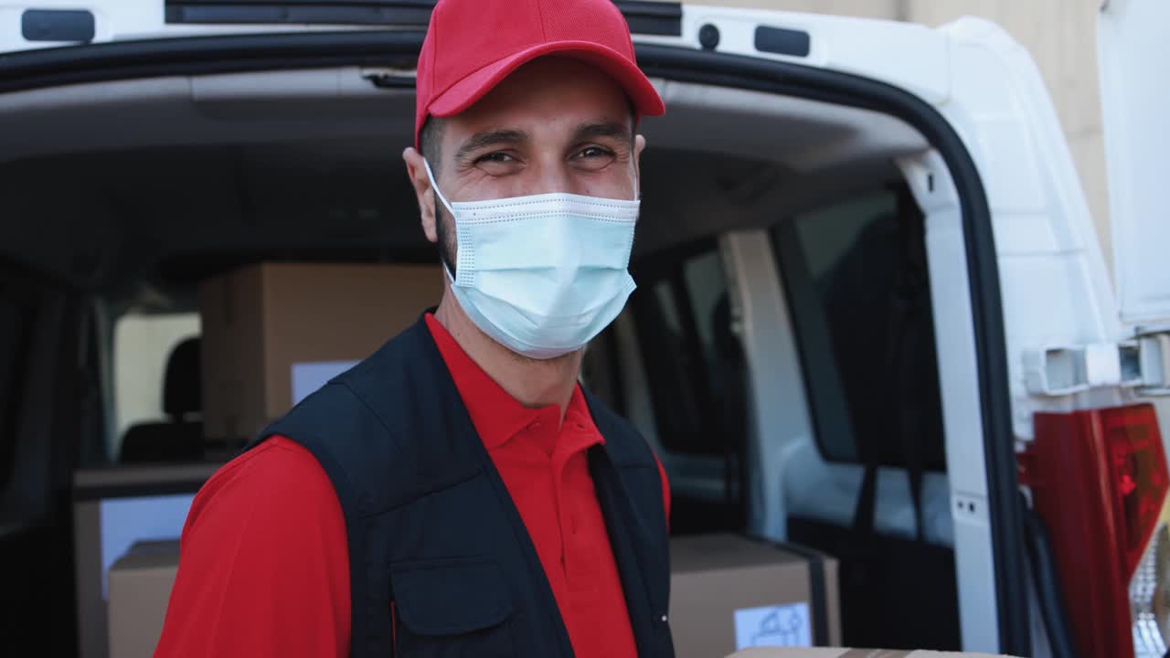 一名白人快递员戴着防护口罩用卡车运送包裹视频素材