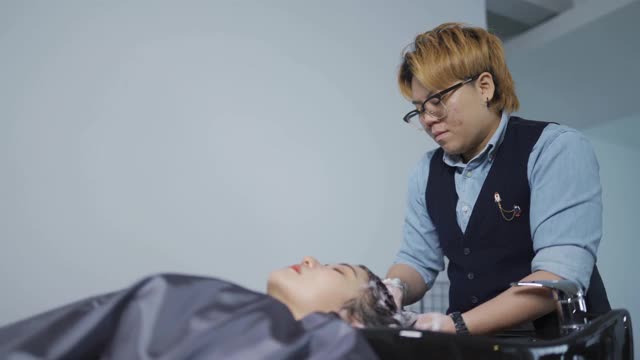 亚洲华人女发型师在发廊为顾客洗头视频素材