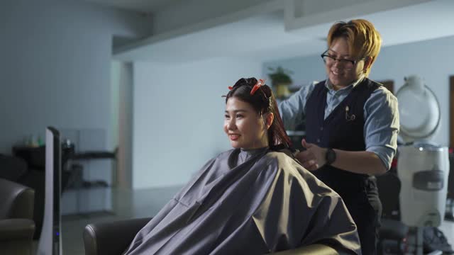 亚洲华人发型师在美发沙龙为她的顾客理发视频素材