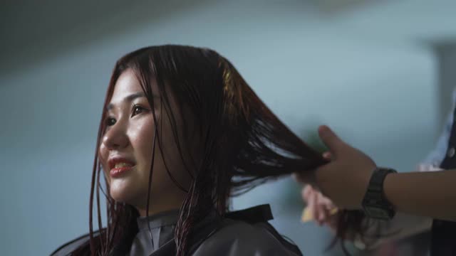 亚洲华人发型师在美发沙龙为她的顾客理发视频素材