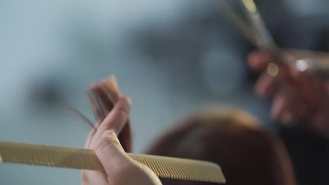 慢镜头亚洲华人发型师在美发沙龙为她的顾客理发视频素材
