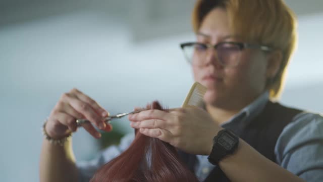 慢镜头亚洲华人发型师在美发沙龙为她的顾客理发视频素材