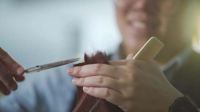 慢镜头亚洲华人发型师在美发沙龙为她的顾客理发视频下载