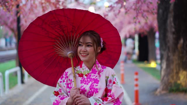 穿着和服的女人在花园里散步，看着樱花或樱花盛开视频下载