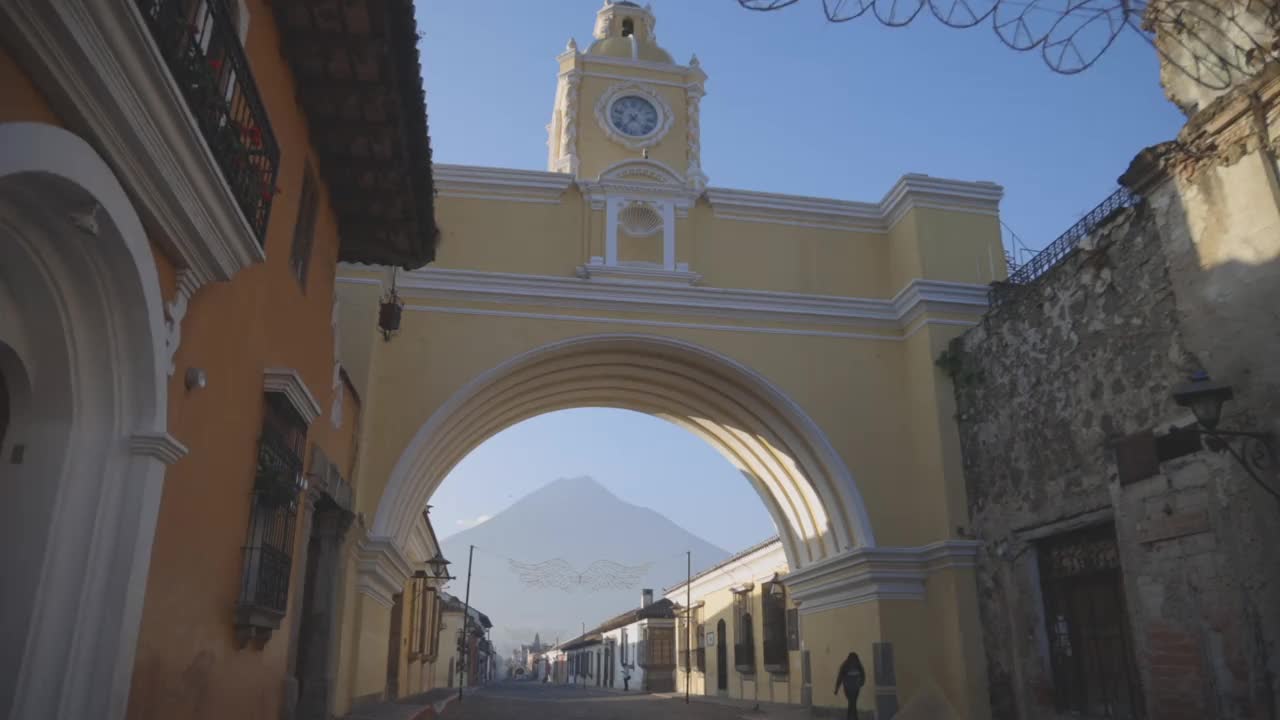 危地马拉安提瓜的圣卡塔琳娜拱门，以清晨的蓝天为背景——危地马拉安提瓜的象征性广场，以水火山为背景视频下载