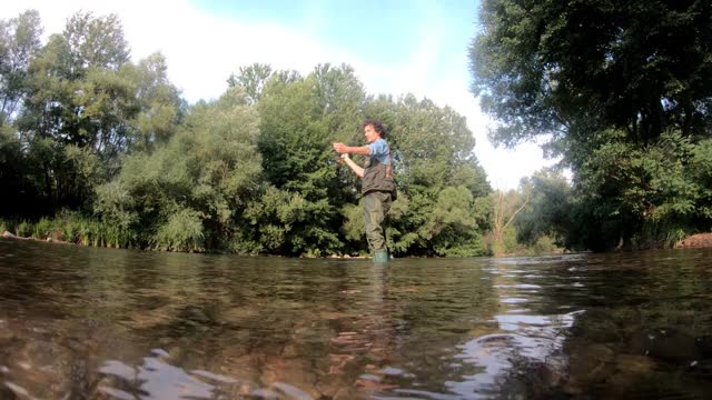 在森林河中钓鱼的渔夫视频下载