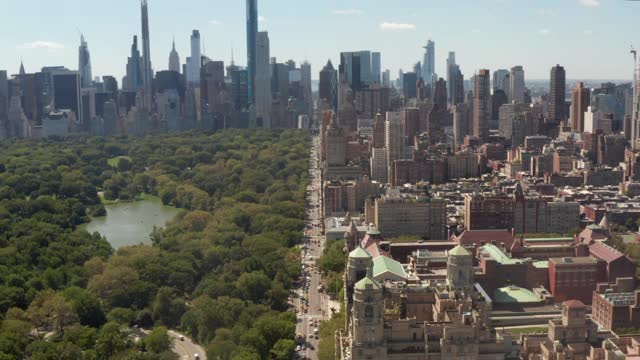 无尽的道路，汽车交通穿过曼哈顿的大城市，旁边是巨大的中央公园，绿色的自然和城市天际线摩天大楼，空中宽推车向前视频下载