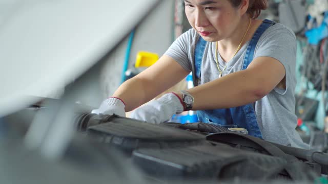 亚洲妇女正在汽车修理店修理汽车。视频素材