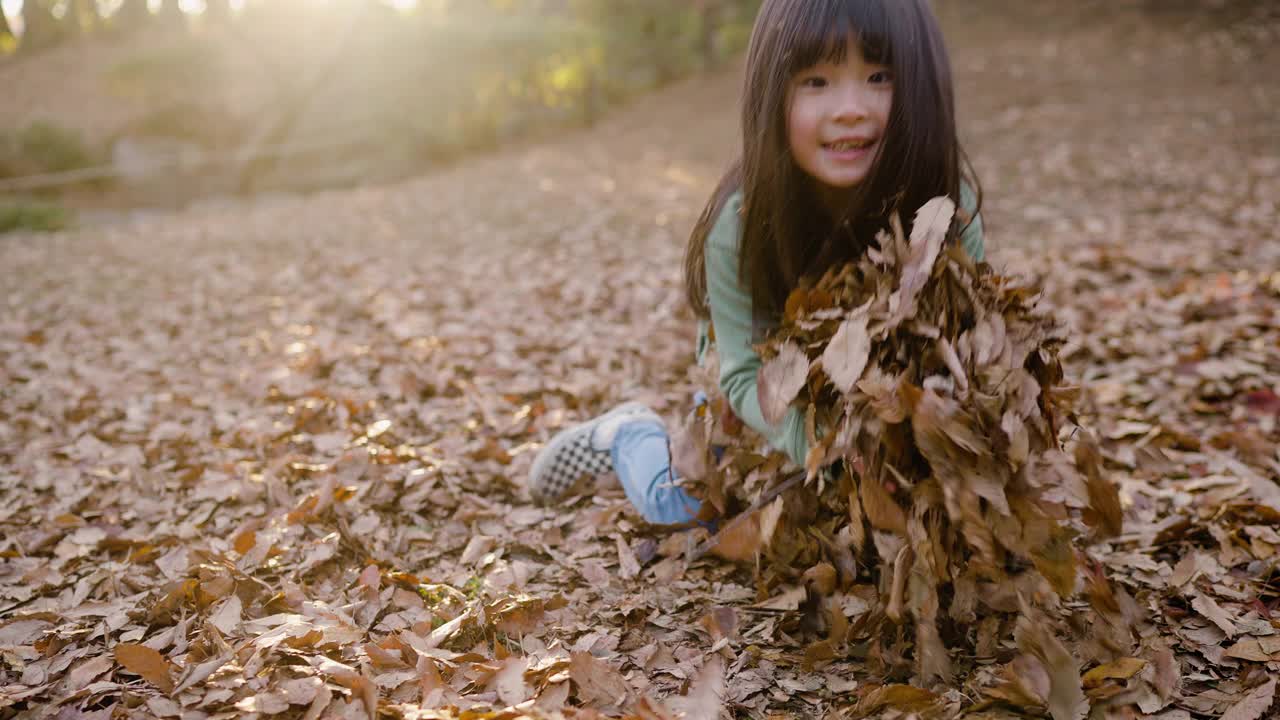 小女孩在公园里玩落叶视频素材