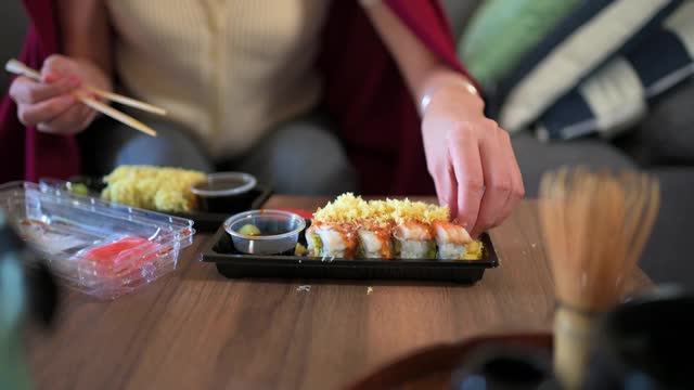 在家吃带酱料的塑料包装寿司卷的妇女视频素材