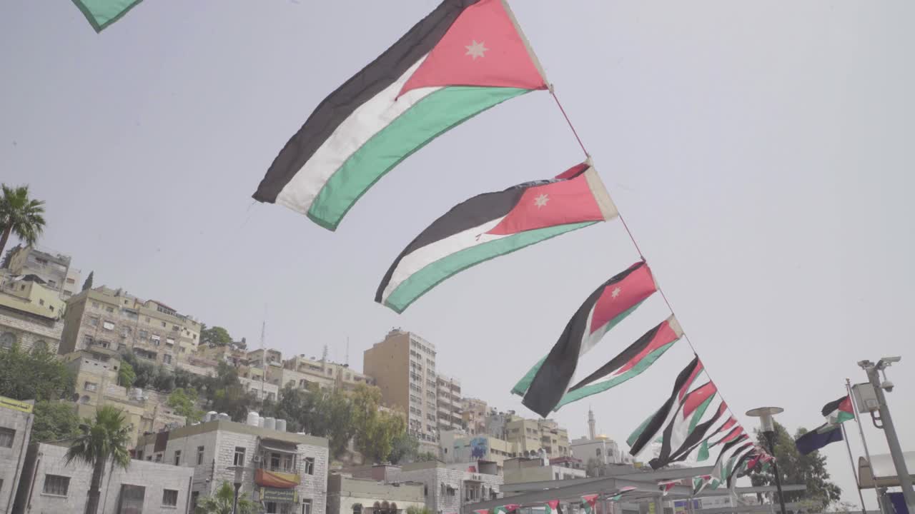 许多约旦国旗在微风中飘扬在约旦安曼街道上的一根绳子上视频下载