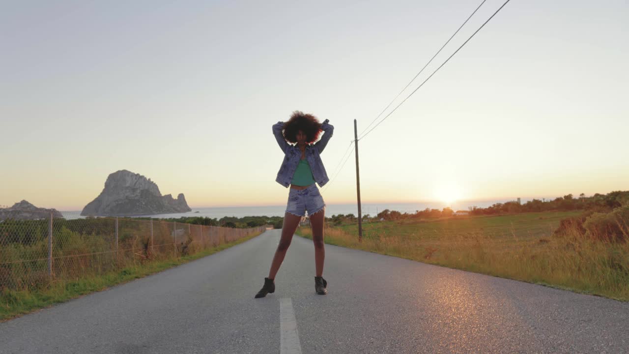 日落时分，年轻女子在马路上摆姿势视频下载