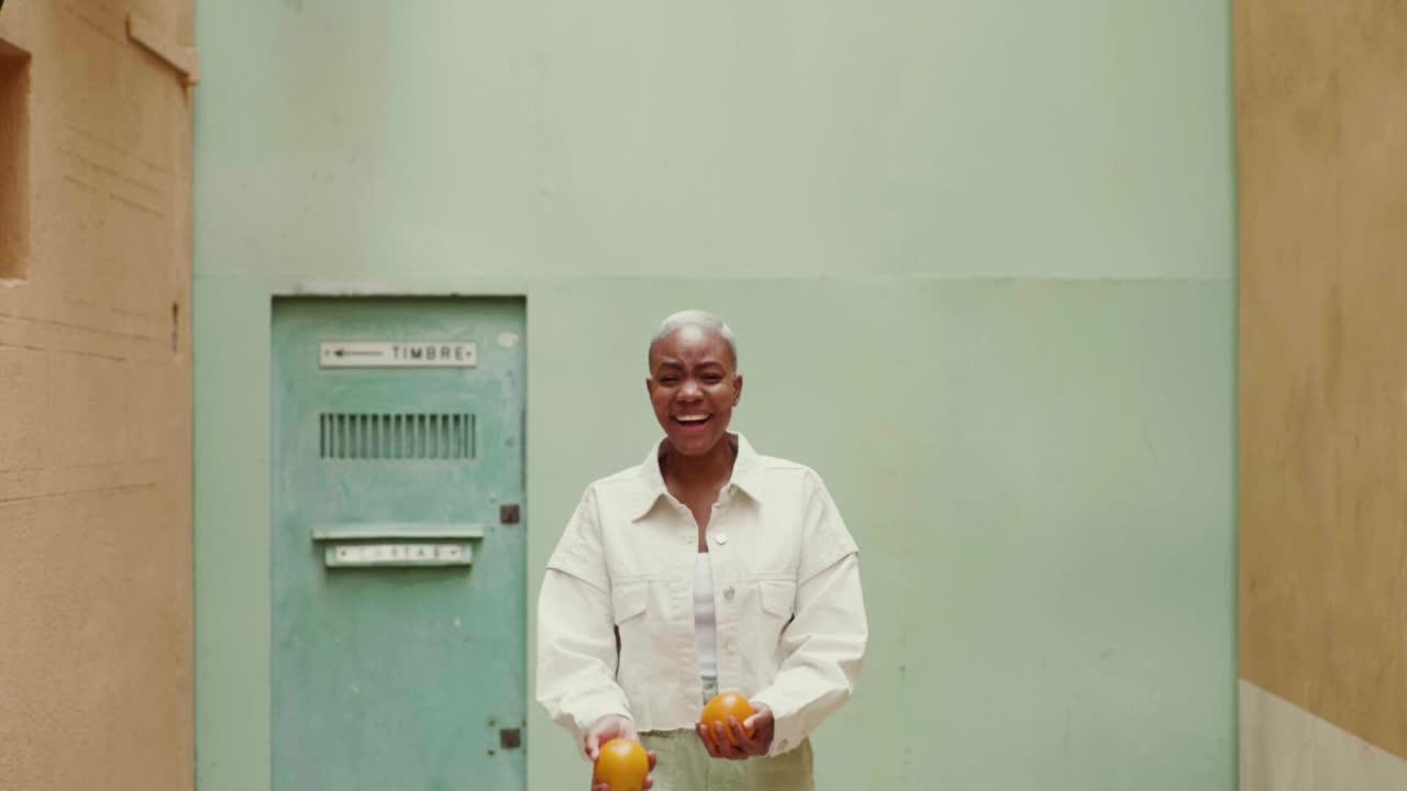 一个快乐女人在户外摆弄橘子的慢镜头视频下载