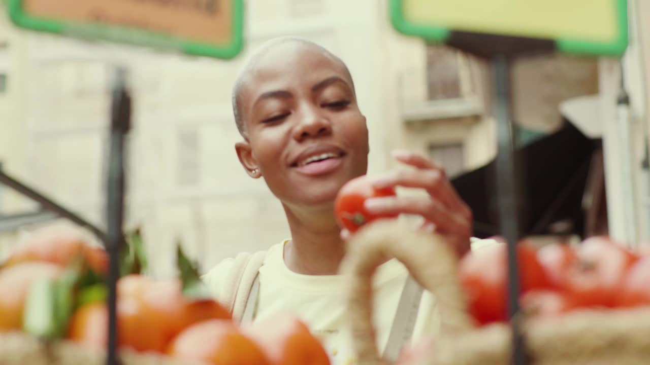 微笑的女人在市场的摊位上买新鲜的西红柿视频下载