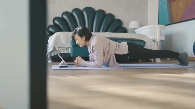 亚洲妇女在垫子上做平板支撑在家视频下载
