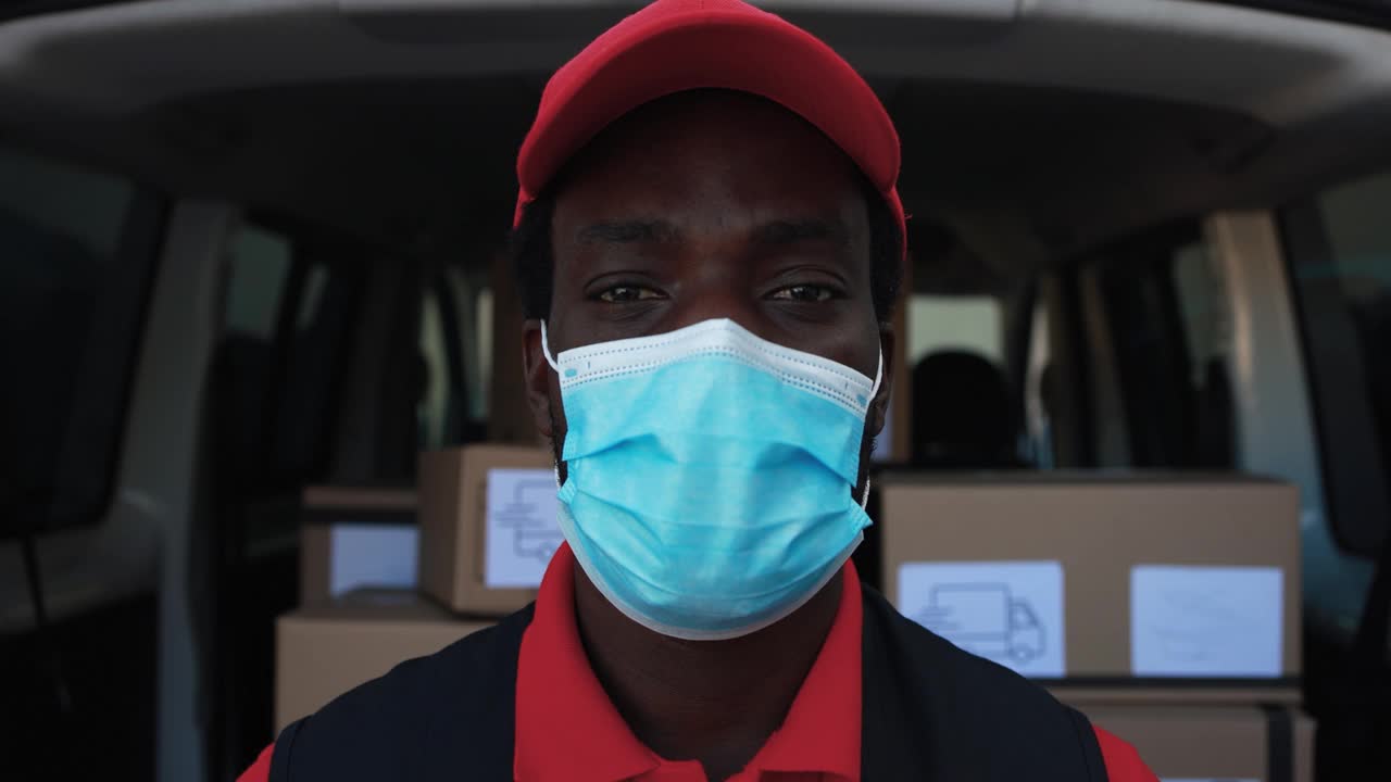 非洲男性快递员戴着防护口罩，用卡车运送包裹视频素材