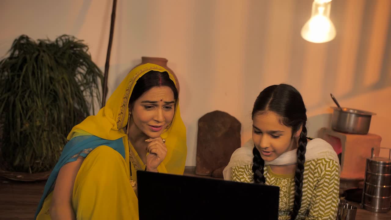 印度一个村庄的年轻母亲和女儿在空闲时间使用笔记本电脑视频素材