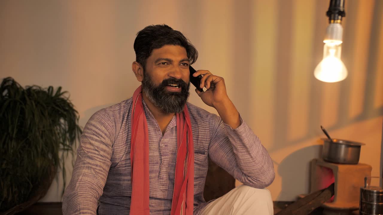 一位英俊的印度中年农民正忙着用智能手机聊天视频素材