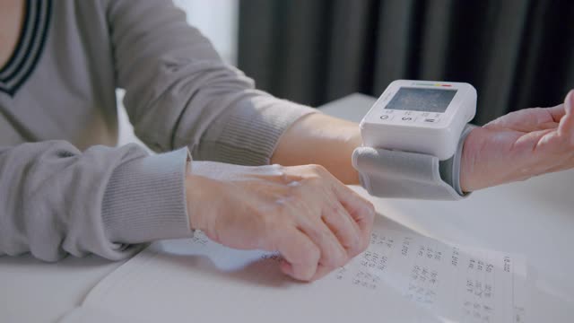 一位年长的妇女使用腕表在家测量自己的血压。视频素材