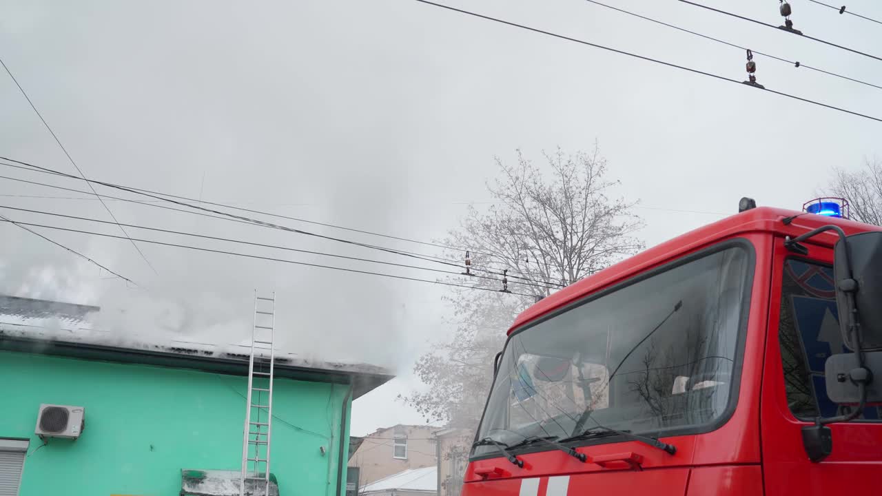 一辆红色的大消防车在冒烟的建筑物附近。视频素材