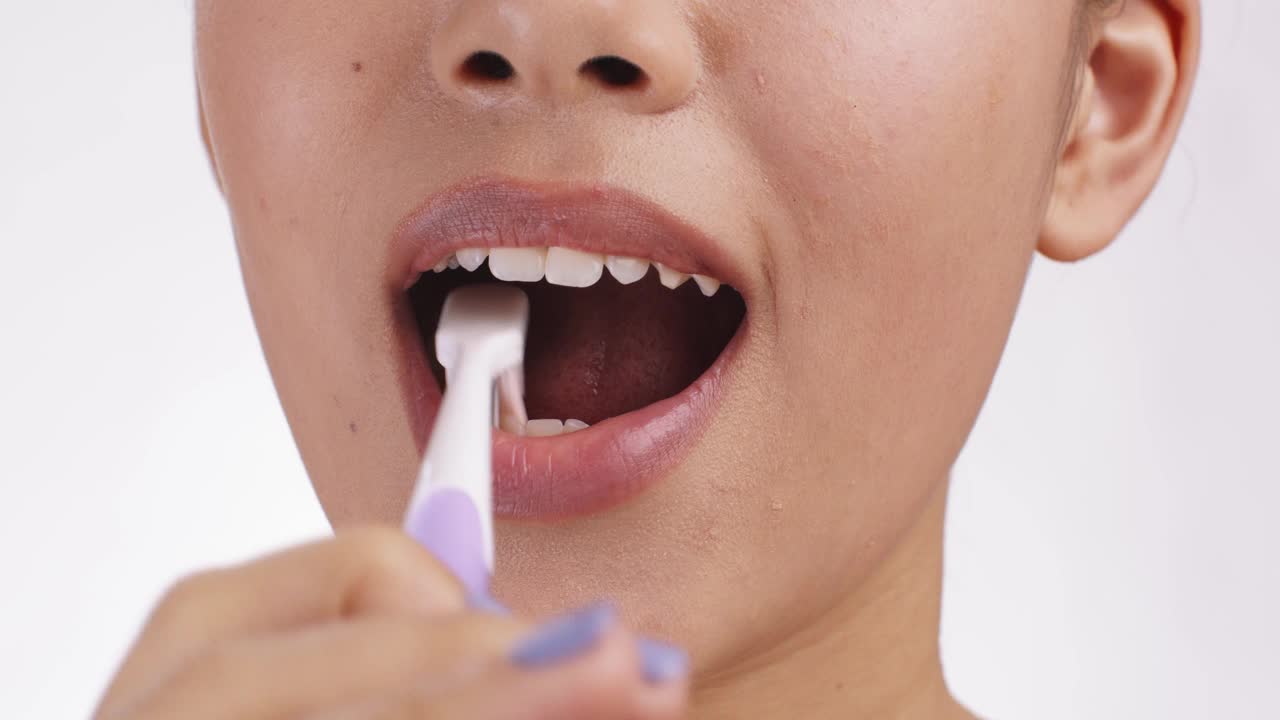 健康的习惯。近距离的年轻女子刷牙她完美的白牙齿，慢动作视频下载