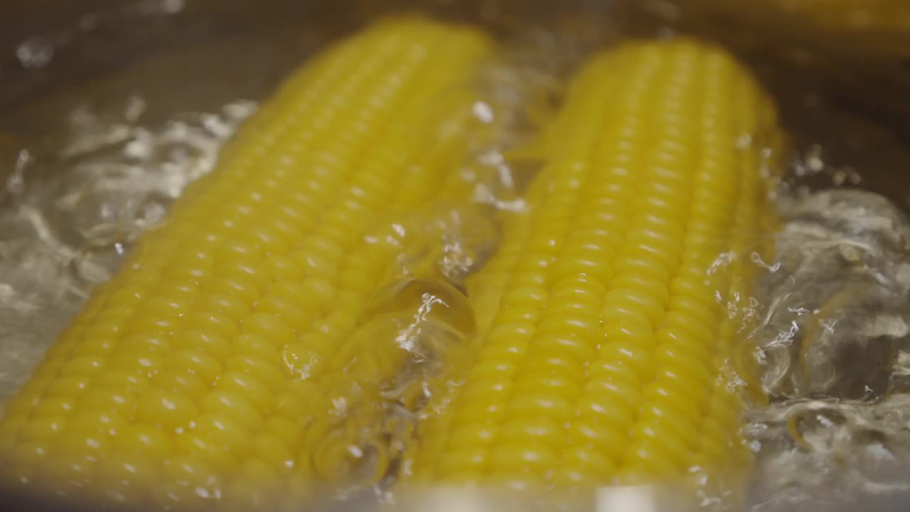 缓慢的运动。熟透的玉米穗放在沸水里，以增进健康。热锅里的黄色玉米。版本2视频素材
