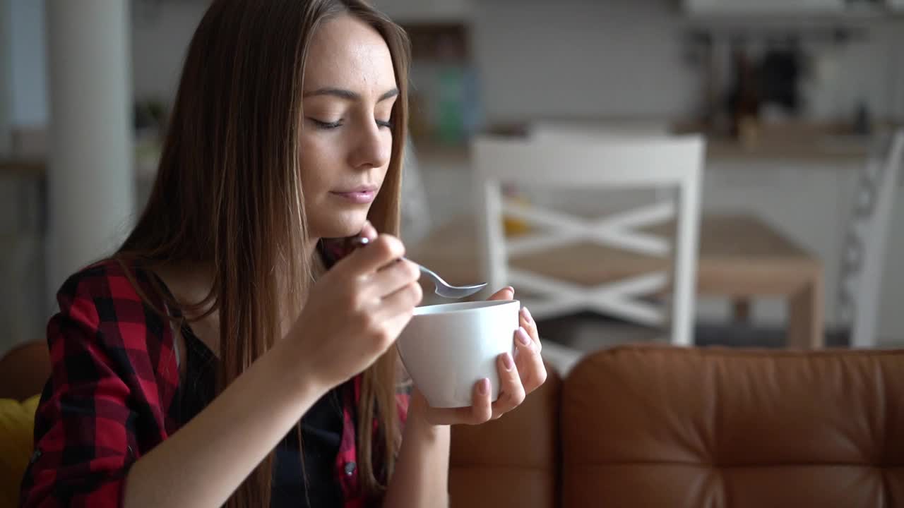 美丽的年轻女子吃一碗健康的格兰诺拉麦片视频下载