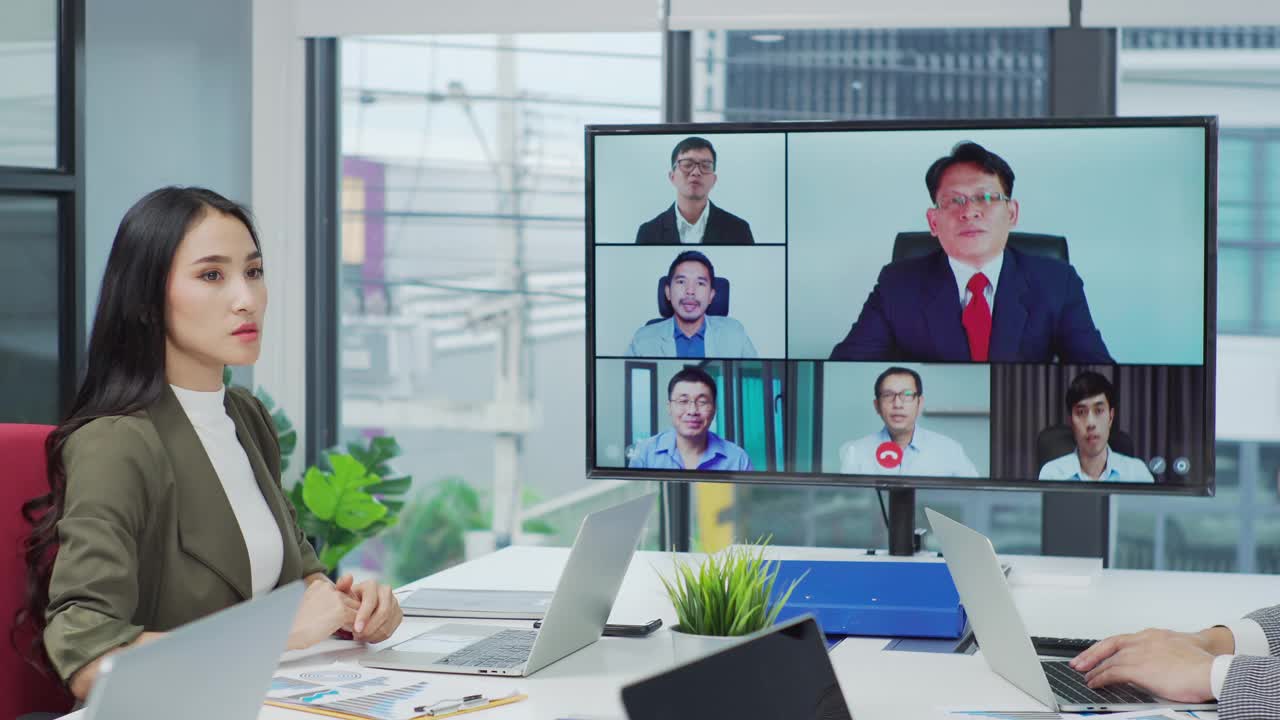 一群商务人士在董事会会议室与一位同事进行视频通话。视频下载