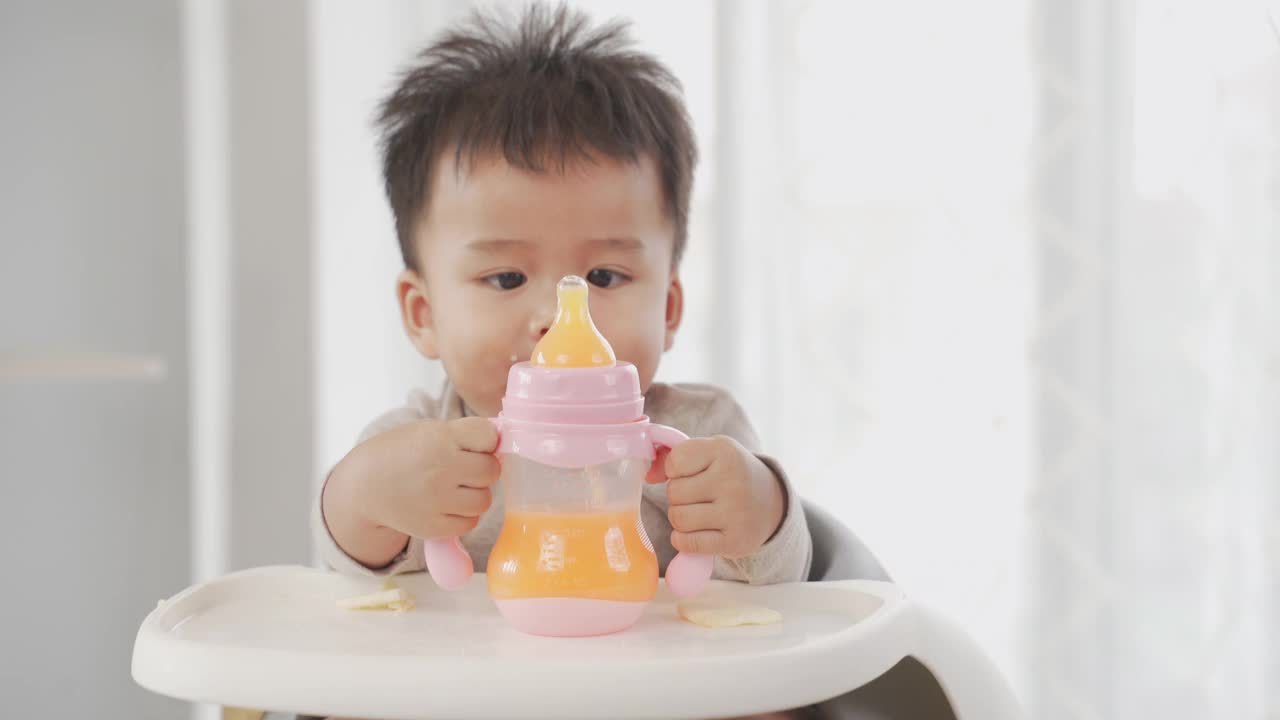 男孩喝着瓶子里的橙汁视频素材