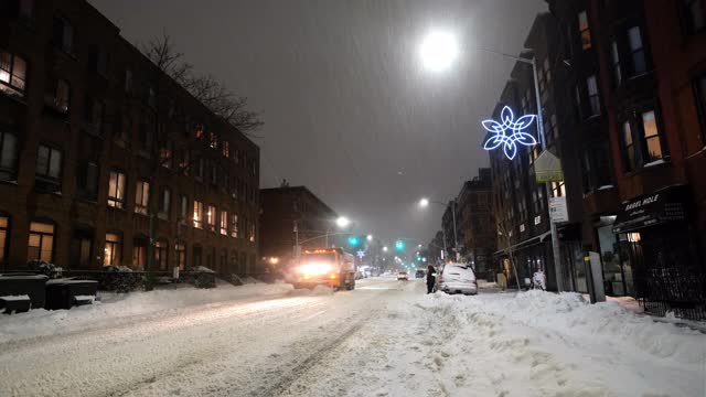 一辆扫雪车在清除街上的积雪。纽约布鲁克林区公园坡(Park Slope)冬天的夜晚，街上下着大雪。视频下载