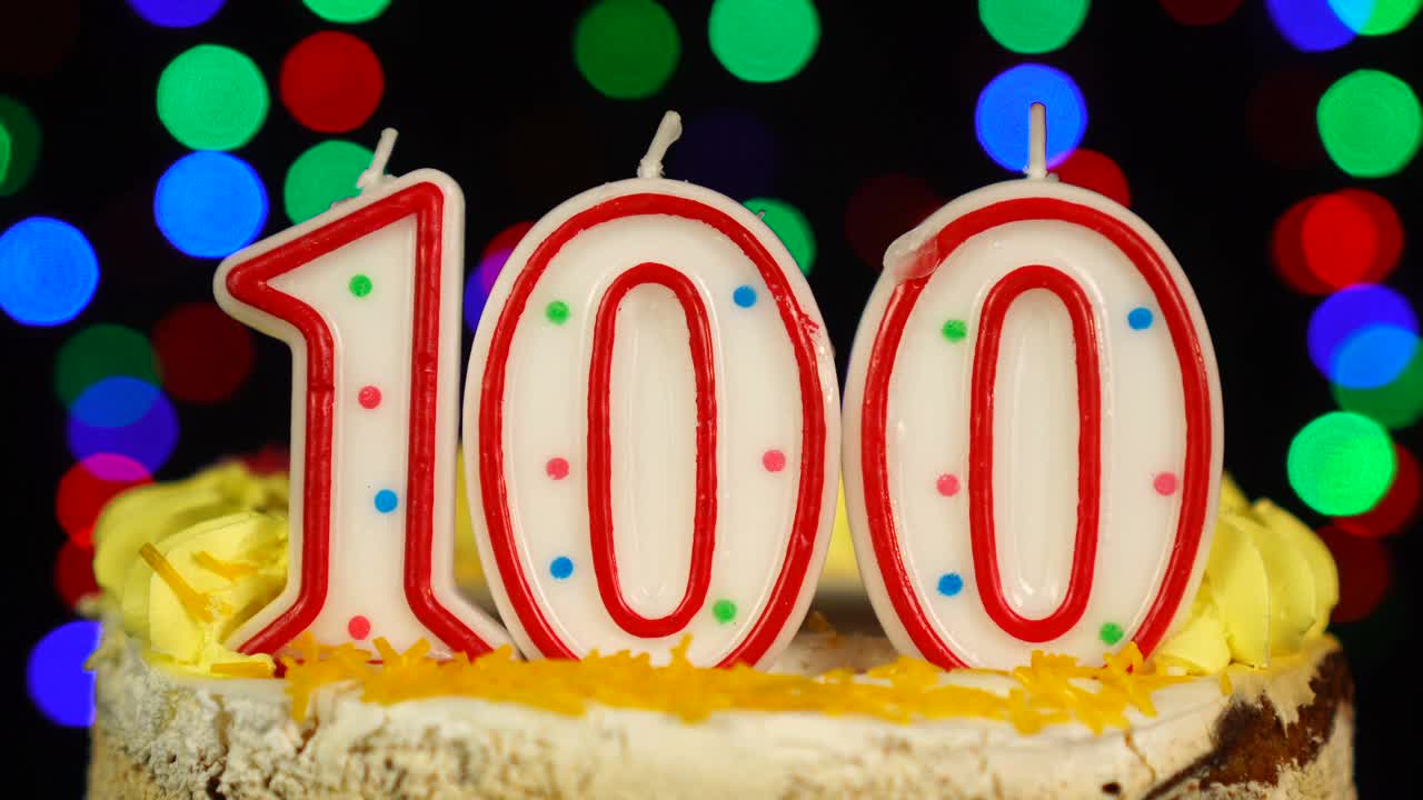 第100个快乐生日蛋糕Witg燃烧蜡烛顶部。视频下载