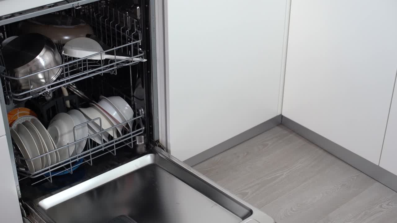 打开洗碗机，里面有干净的餐具。视频素材