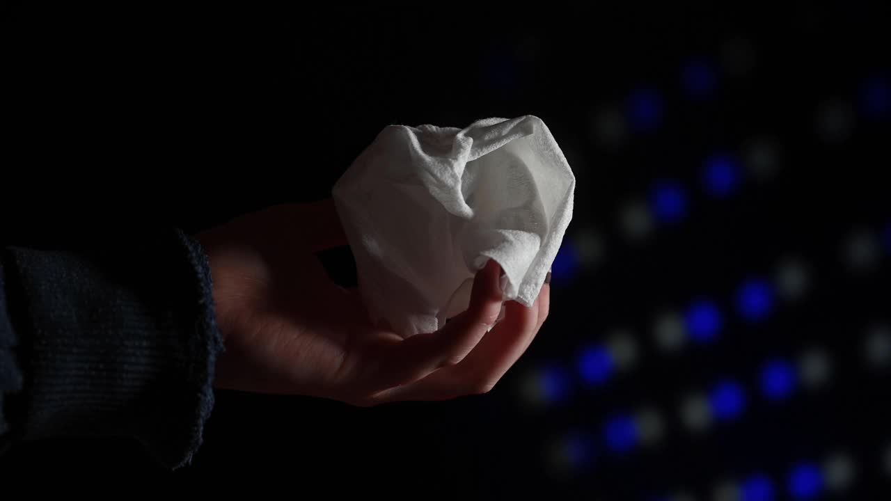 在迪斯科/彩灯闪烁的节日气氛中，女人的手拿着用过的湿纸巾。视频下载