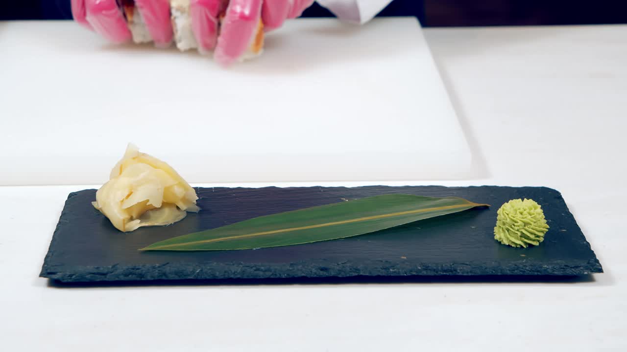 金枪鱼寿司卷的特写。男厨师戴着手套把寿司放到盘子里。视频素材